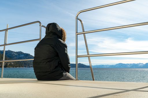 Lifeguard in a warm hooded jacket sits on lifeguard's watchtower on the beach watching the sea in cold weather