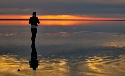 A young female enjoying a beautiful seascape view during scenic sunset in Elton Lake, Russia