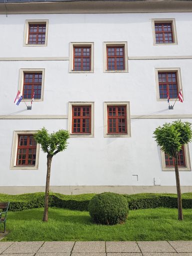 A low angle shot of a building white facade with hanging flags