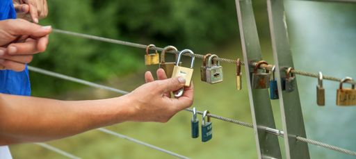 A closeup shot of hands hanging locks on a rope - concept of love