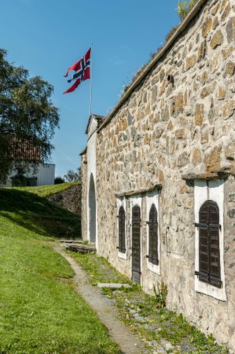 A vertical shot of a flag and a part of the Kristiansten Fortress in Trondheim, Norway