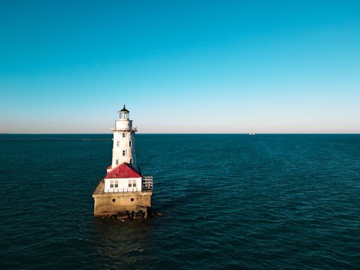 A bird's-eye view of a lighthouse in the middle of an ocean