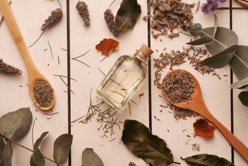 A beautiful flat lay with various spices and natural leaves with an empty flask in the center, perfumery concept