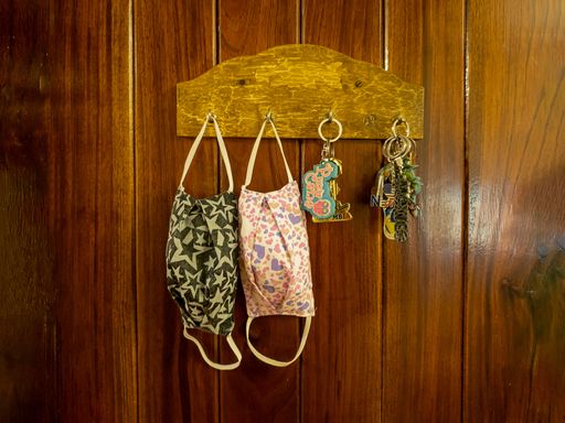 A close up shot of medical masks and charms on hanger attached to wooden wall