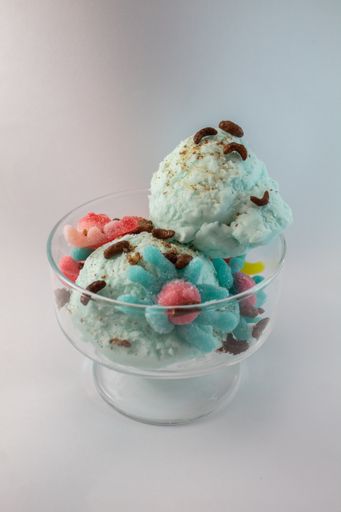 A vertical closeup shot of chocolate mint ice cream in a small vase with a grey background