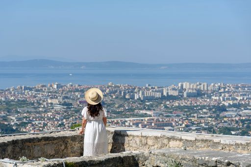 The rear view of a woman standing at Klis fortress overlooking the city of Split, Croatia