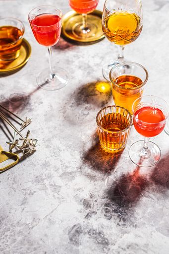 A vertical high angle shot of glasses filled with different drinks on a glass surface