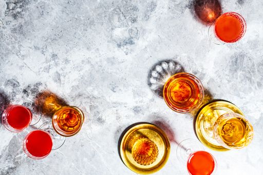 An overhead shot of glasses filled with different drinks on a glass surface