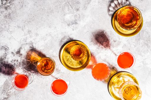 An overhead shot of glasses filled with different drinks on a glass surface
