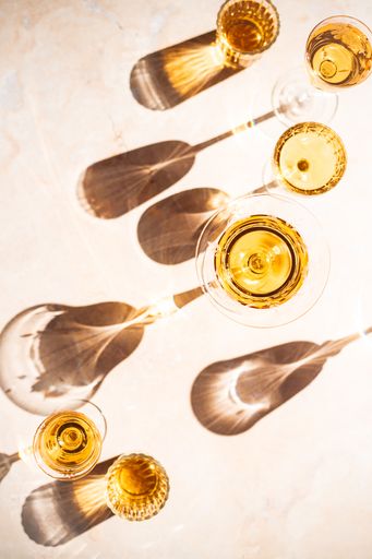 A vertical high angle shot of glasses of white wine with reflections on the ground