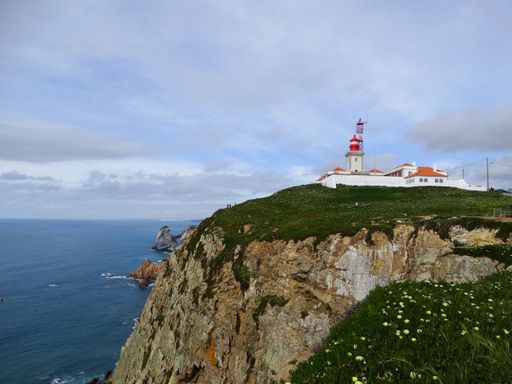 A beautiful view of Cabo da Roca Lighthouse on the cliff and a calm sea in the background in Portugal