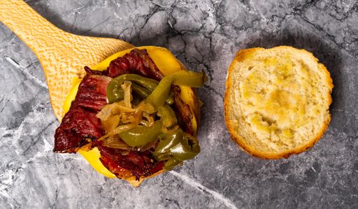 A top view of a delicious burger with pastrami, pickled peppers and cheese being prepared