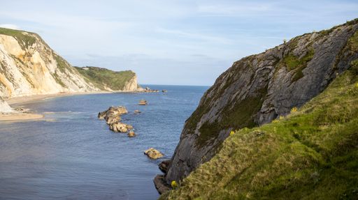 A beautiful shot of a sea with rocky mountains. Morning sun shines on cliffs at Man O'War Bay near Durdle Door ,England, UK