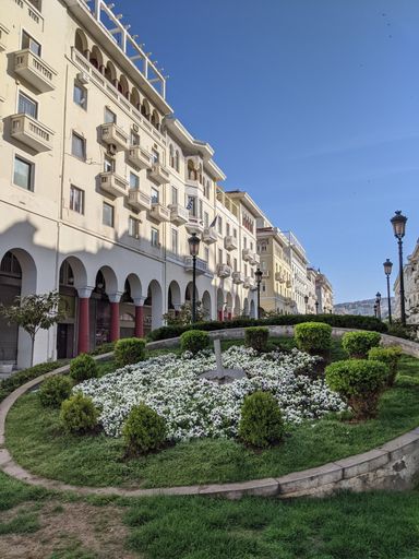 A vertical shot of a beautiful building and green space near Aristotelous Square in Thessaloniki