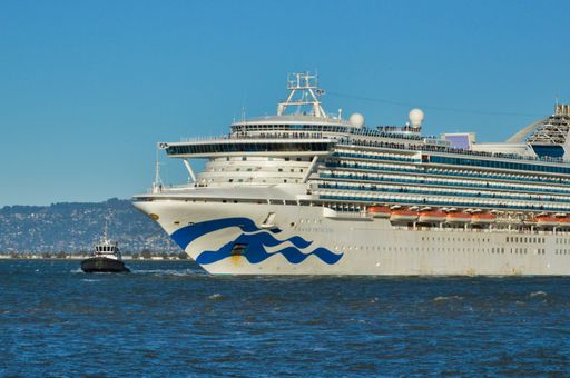 A big cruise ship named Princess near tow boat in the ocean and clear sky on the top