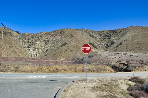 A view of road surrounded by greenery hills with stop road sign in red