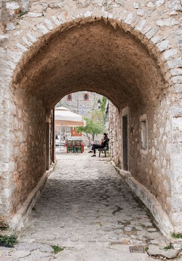 A woman sitting on a bench at the end of a tunnel