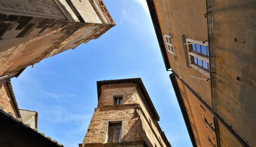 A low angle shot of towers of Palazzo Ubaldini Ivarra buildings with a blue sunny sky, Italy
