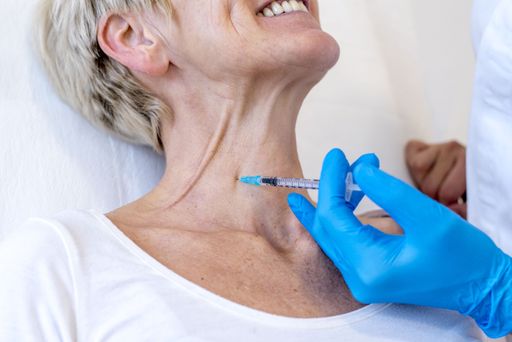 A closeup of a cheerful old female getting neck botox in a hospital