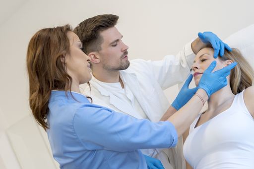 Two doctors checking the face of a patient before performing a cosmetic surgery