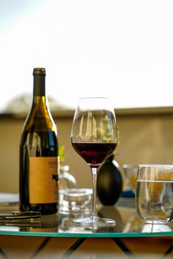 A vertical shot of a glass of wine with a bottle and water on a table