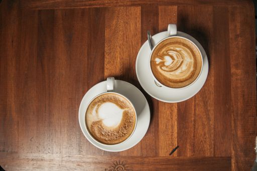 A high angle shot of two cups of coffee with cute hearts on a wooden table