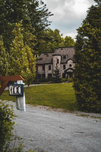 A vertical shot of stony building surrounded by green trees near road