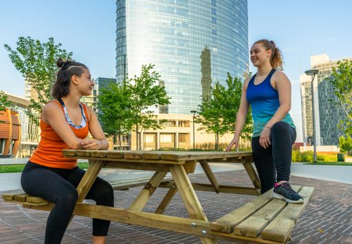 Two Caucasian women friends sitting on the table bench in the park