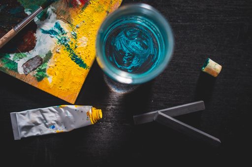 A high angle shot of a painting colour board with other tools on a black table