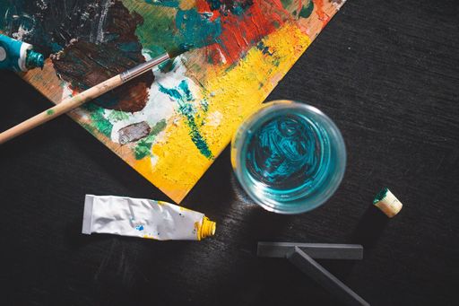 A high angle shot of a painting colour board with other tools on a black table