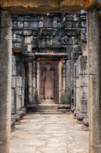 A vertical shot of the interior of an old Buddhist building in Sri Lanka with a Buddha statue in the background