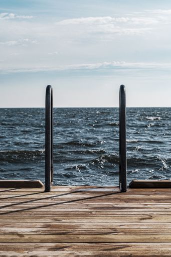 A vertical shot of a wooden pier in the lake
