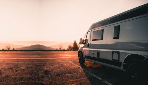 A campervan parked on the side of the road against a scenic sunset