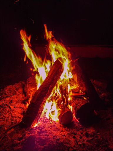 A vertical shot of burning firewood logs in the dark