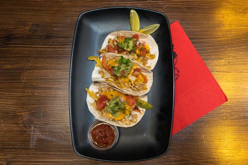 A top view of delicious tacos with salsa on a tray on the table