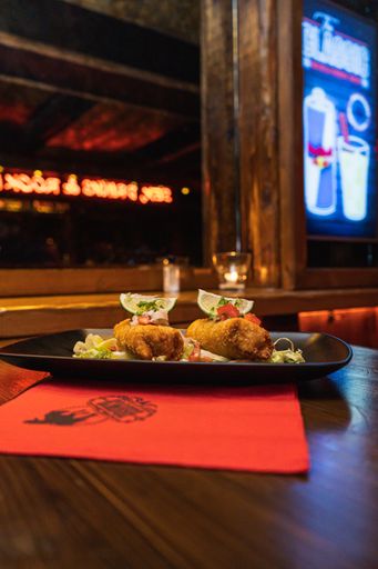 A vertical shot of fried mozzarella sticks with lime and salad in a black plate on the table