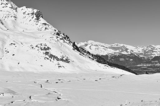A grayscale shot of a winter landscape with a river serpentine and snowy mountains in Switzerland