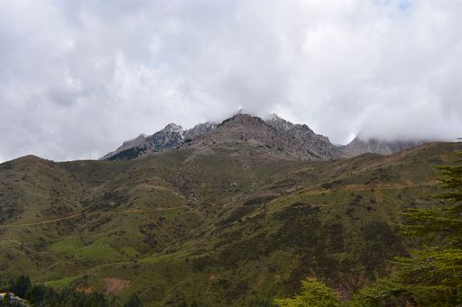 The low-angle view of the mountain top against the cloudy sky
