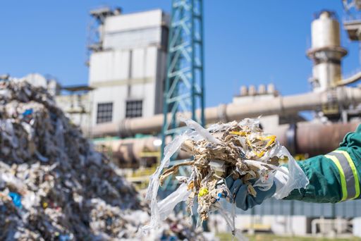 A selective focus shot of a person wearing gloves holding shredded municipal waste
