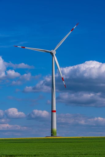 A single windmill in the green field against a cloudy sky