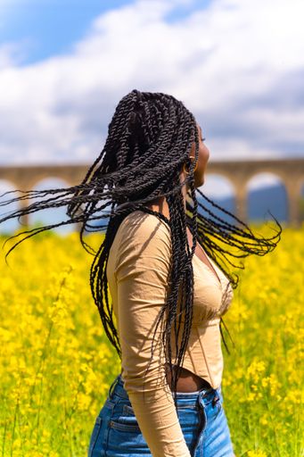 A young African-American female with braids in a bright yellow field of rapeseed