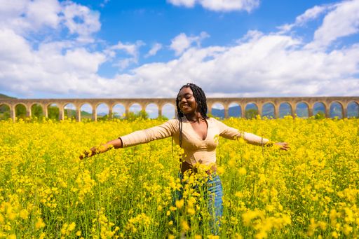 A young beautiful African-American female with braids in a bright yellow field of rapeseed