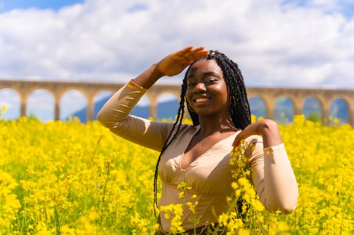 A young beautiful African-American female with braids in a bright yellow field of rapeseed