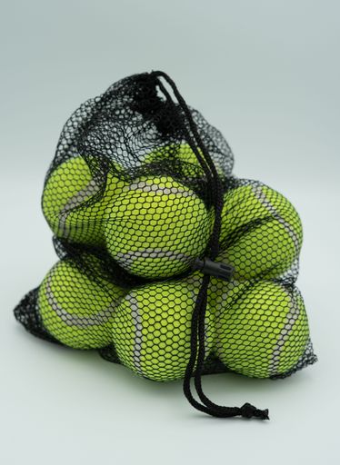 A vertical closeup shot of tennis balls in the black net bag isolated on the white background