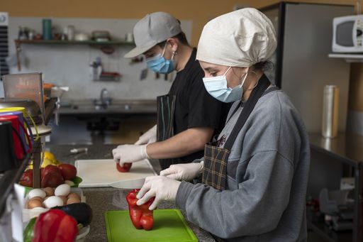 Two Hispanic chefs cooking in the kitchen wearing protective medical face masks - COVID-19 prevention concept