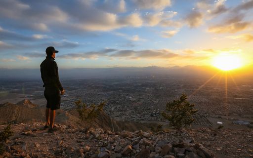 A solo hiker watches the sunset from atop Las Vegas' Frenchman Mountain, a challenging hike on the east side of the Las Vegas Valley.