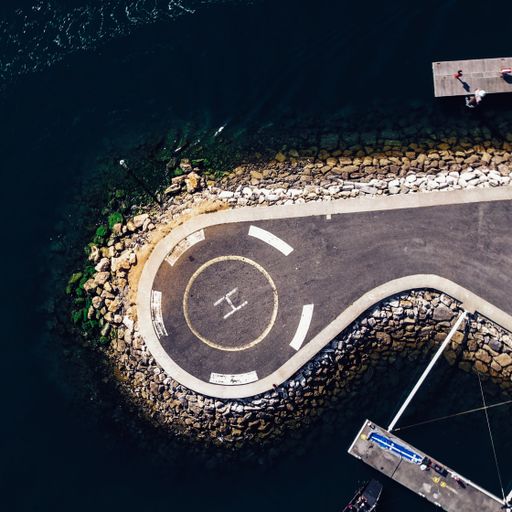 A top view of the spiral towards helicopter helipad on the seashore next to the boats on the water