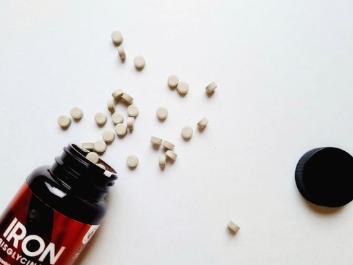 From the inverted jar, iron supplement pills come out onto the white surface of the table. Top view