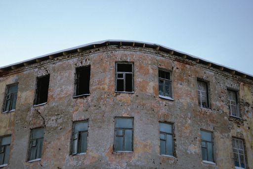 A low angle shot of the exterior design of an abandoned building with broken windows