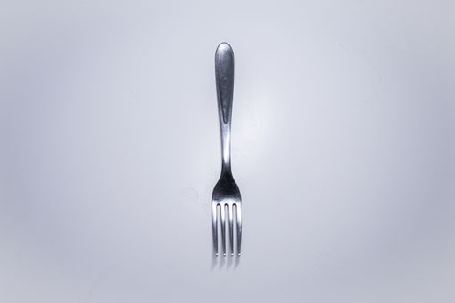 A top view of a silver fork on a white surface with a copy space